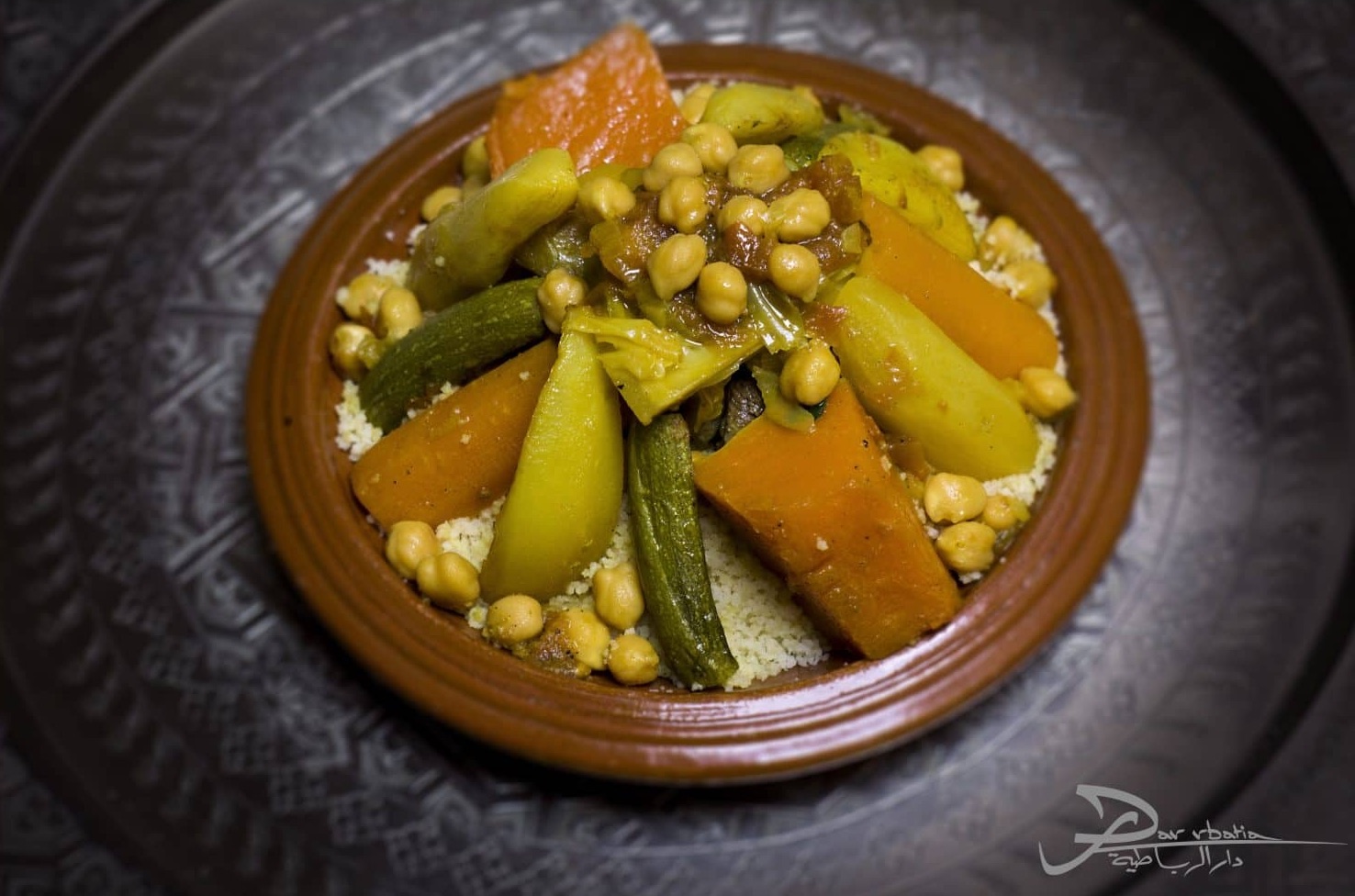 Couscous aux sept légumes et pois chiches dans un plat en terre cuite